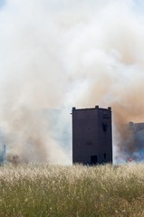 Fototapeta na wymiar Ancient tower surrounded with wheat and with smoke