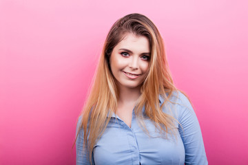 Portrait of beautiful blonde woman smiling on pink background