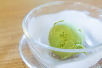 green tea ice cream scoop in glass bowl on wooden table in japan restaurant