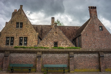 Fototapeta premium A bench in front of a building with red bricks in Brugge