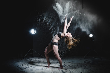 Obraz na płótnie Canvas Girl dansing with flour on black background