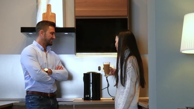 A beautiful young couple having a coffee and a chat together in the kitchen.

