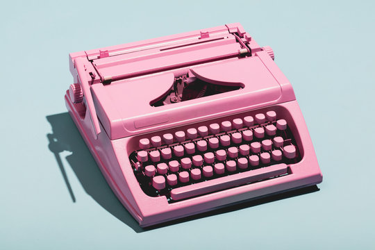 Pink typewriter on a blue pastel background.