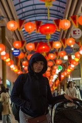 Obraz na płótnie Canvas Young woman in arcade in Japan with lanterns overhead.