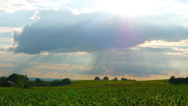 Sunshine breaking through clouds over a idyllic landscape	in Germany.
