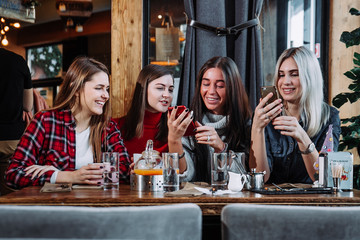 four friends look at the phone and laugh