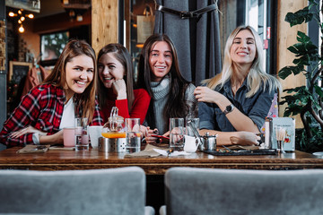 four friends in the cafe look at the camera and laugh