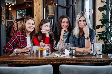 four friends in the cafe look at the camera and laugh