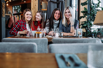 four friends in the cafe look at the camera and laugh