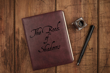 Leather bound journal titled The Book of Shadows, a witch's grimoire, and ink well and pen
