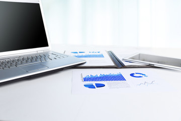 Financial chart, laptop and tablet on the workplace of a businessman