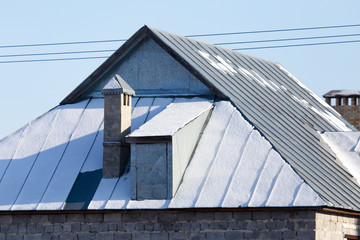 Snow on the roof of the house in winter