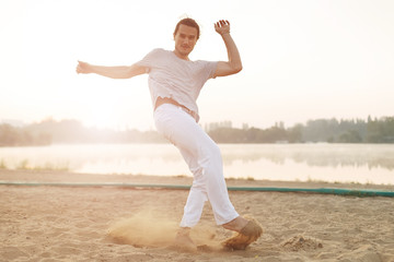 Obraz premium Athletic capoeira performer making movements on the beach