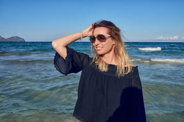 Hübsche blonde Frau am Strand lächelt