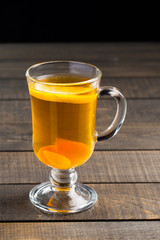 A cup of ginger tea with lemon on a wooden background.