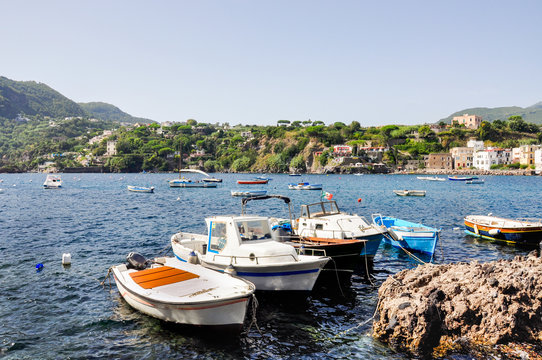 Italian summer holidays in Ischia, blue sea and sky on a Sunny day, beaches and houses on the coast, many white yachts and boats