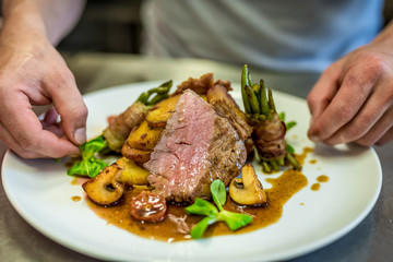 Closeup of the hands of a chef decorating a meat steak