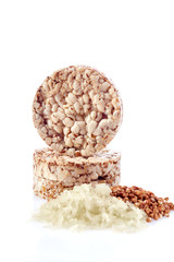 Diet rice cakes pile with buckwheat and rice grains isolated on white background, vertical, selective focus