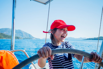 Little boy captain on board of sailing yacht on summer cruise. Travel adventure, yachting with...