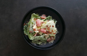 caesar salad serving on black bowl on dark table
