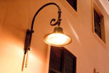An old street lamp on a house with windows.