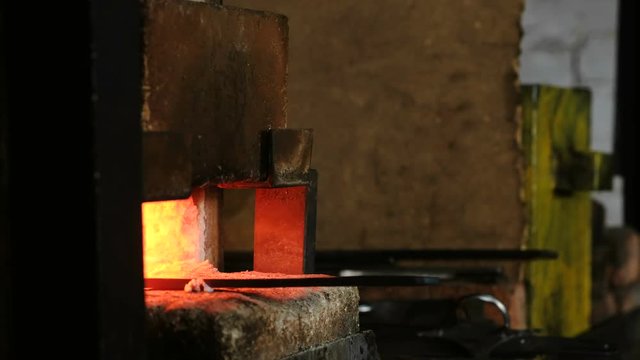 Making the sword out of metal at the forge. Blacksmith's hand pulls out of the furnace hot metal blanks.