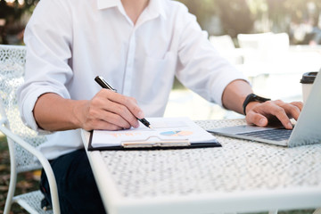 Businessman using computer at park outside office.