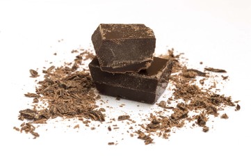 piece of dark chocolate with shavings on white background