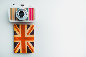 Camera and a passport in the cover of the English flag lie on a felouple isolated background, a copy of the space