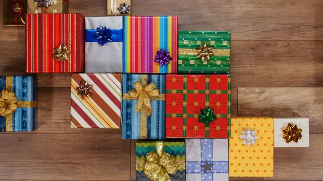 Lots of colorful wrapped presents gather on wooden surface, covering the whole screen - variety of gifts for christmas or other occasions, stop motion animation