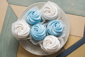 four cakes on a plate, top view. White meringue with chocolate.
