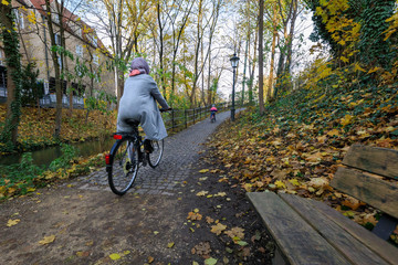  Frau mit Kind fährt Rad auf einem Radweg in der augsburger Innenstadt im Herbst