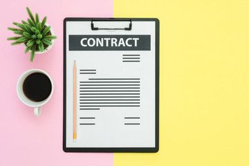 Flat lay design of office desk working space  - Top view of a contract document and coffee cup decorated with small cactus on pink yellow pastel color with copy space. Pastel working space background.