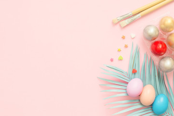 Flat lay top view colorful easter egg painted in pastel colors composition with paint brush on pink pastel color background. Easter day background top view with copy space.