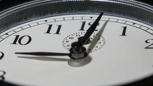 Closeup on slowly rotating clock face with fast moving clock hands - time running out concept, timelapse