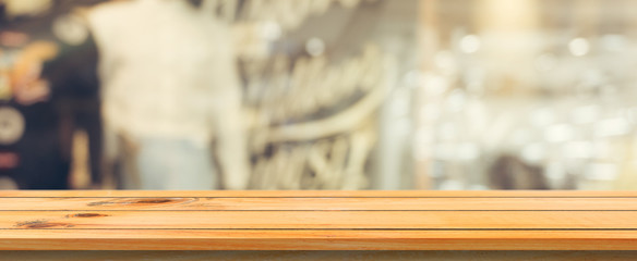 Wooden board empty table top blurred background. Perspective brown wood table over blur in coffee shop background. Panoramic banner - can be used mock up for montage products display or design.