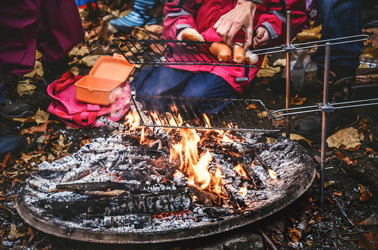 Open barbecue fireplace outside in the autumn season.. Roasting swiss sausages called in German Cervelat and Bratwurst.