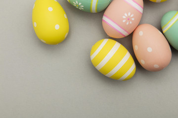 Easter holiday background. Pastel coloured decorated easter eggs on a grey background