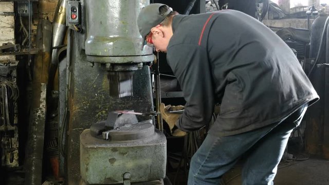 Making the knife out of metal at the forge. Man using pneumatic hammer to shape hot metal.