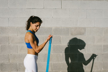 Fitness young woman doing biceps curl with resistance band for training arms strength. Female...