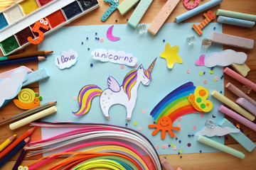 applique with a picture of a unicorn and a rainbow with children's chalk and pencils on a wooden...