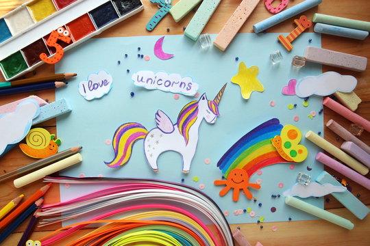 applique with a picture of a unicorn and a rainbow with children's chalk and pencils on a wooden background