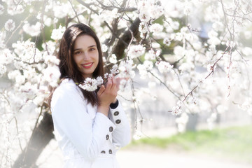 Portrait of a young woman against a background of blossoming apricot