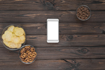 chips, crackers, snacks, a smartphone on a wooden background. view match, transfer.