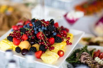 Berries and fruits: strawberries, raspberries, blackberries, blueberries, red currants, bananas, lie on a plate.