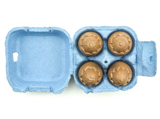 Four chocolate eggs in a blue box isolated on white background top view.
