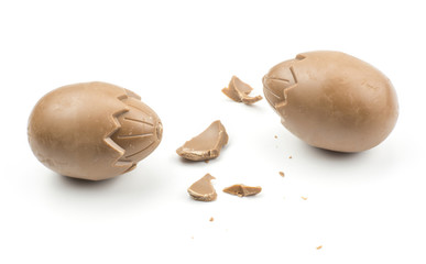 Two chocolate eggs with cracked pieces isolated on white background.