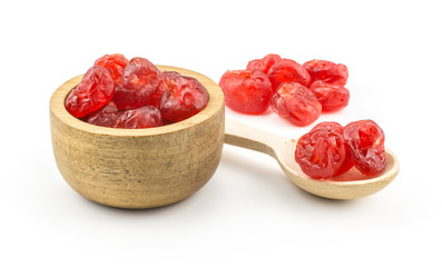 Red dry cherries in a wooden bowl with a spoon isolated on white background.