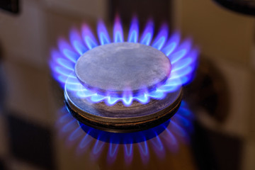 The gas is burning, the gas-stove burner, the hob in the kitchen, close-up. The concept of problems with natural gas, rising gas prices.
