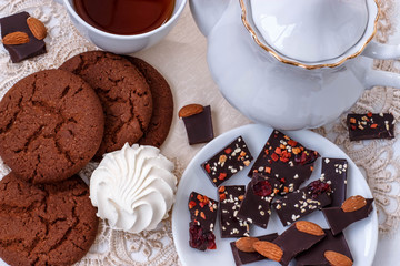 white still life with a Cup of black tea, black fruit chocolate and biscuits